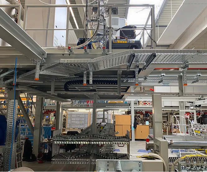 Industrielle Fabrikhalle mit großen Metallstrukturen und Förderbändern unter Tageslicht.