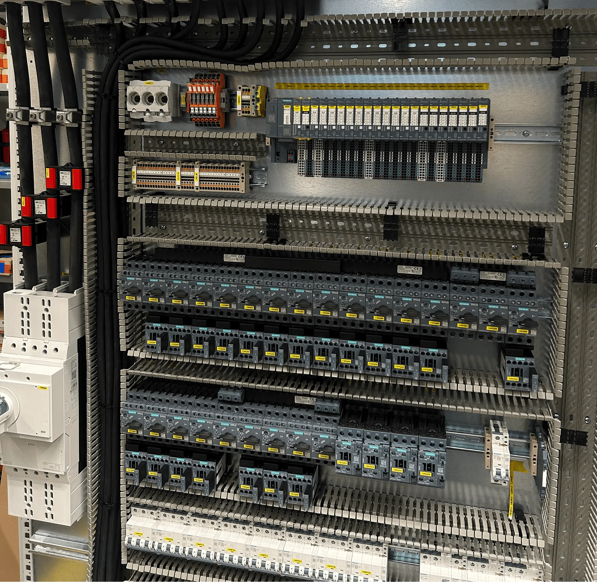 Elektrischer Schaltschrank mit mehreren Reihen von Sicherungen, Schaltern und Kabeln.