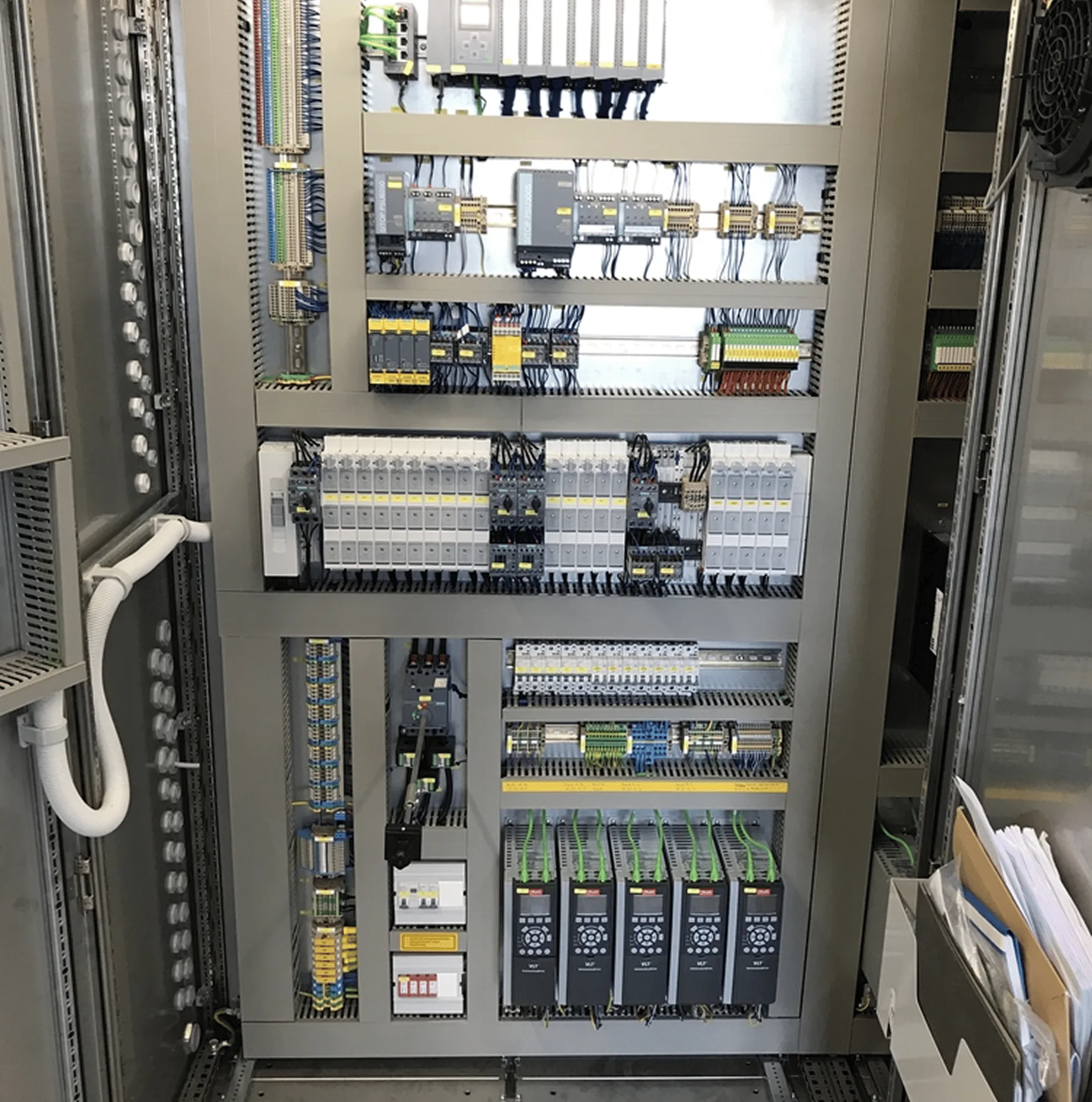 Innenansicht eines offenen elektrischen Schaltschrankes mit verkabelten Steuerungs- und Automatisierungskomponenten.