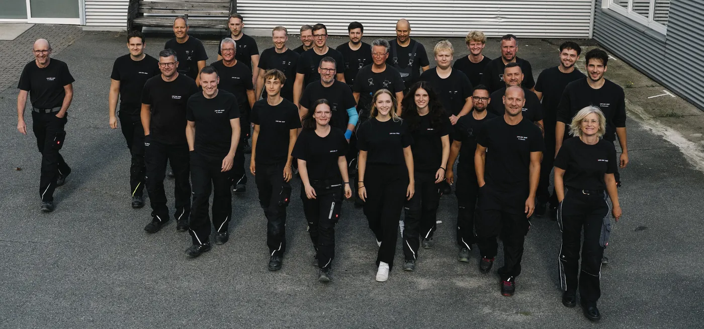 Das Team der ElektroTechnik Lüneburg in schwarzer Arbeitskleidung auf dem Firmengelände.